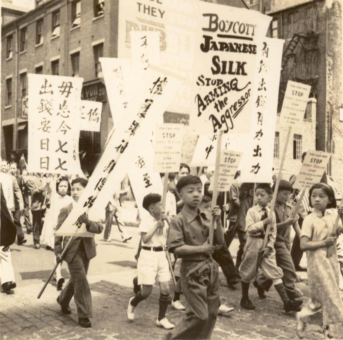 black and white image of young students holding signs in boycott of Japanese silk