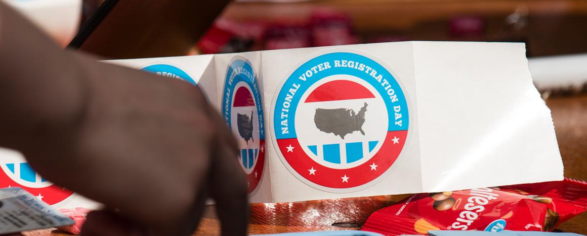Red and blue round stickers that read "National Voter Registration Day" with an image of the U.S. in the center