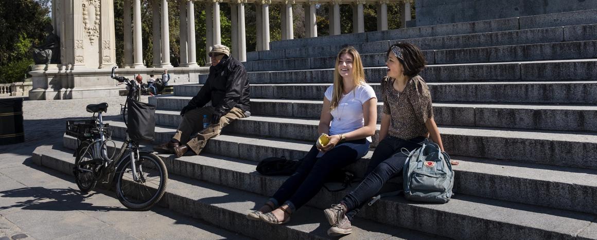 three people sitting on stone stairs outside of a building