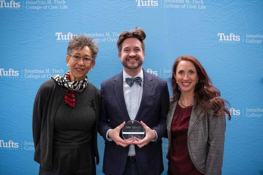 Two woman posing with a man who won a Tuft's Award