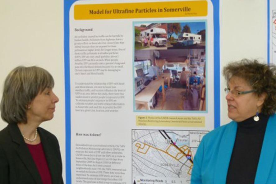 Two women behind a poster of TCRC research