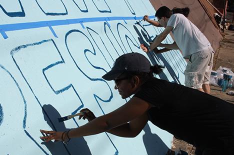 two people working on wall art