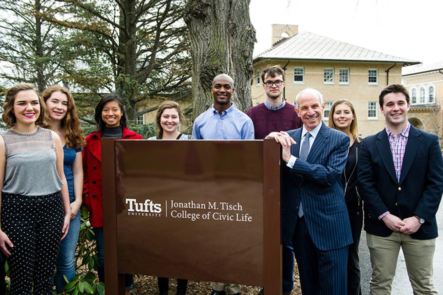 Jonathan Tisch standing at a sign with students