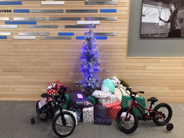 small blue tree surrounded by gifts and two bicycles