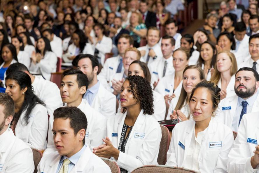Tufts medical students in their white coats clapping