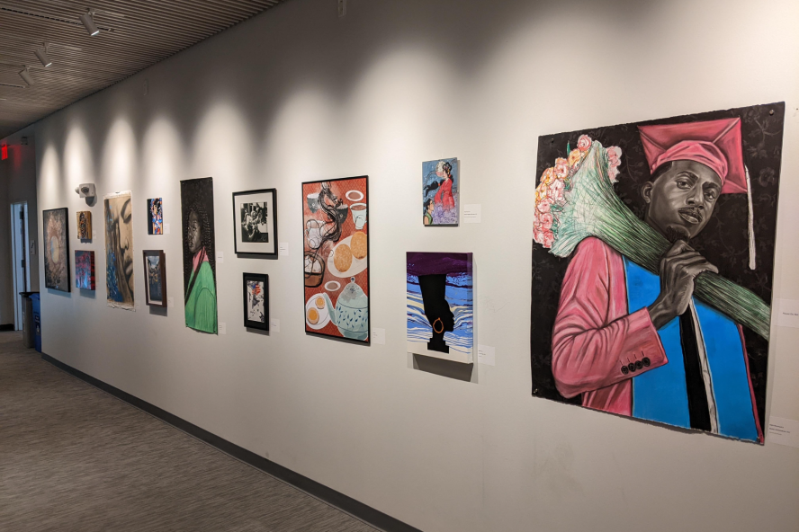 Artwork on the wall of Barnum Hall Lobby, the first is a painting of a young black man in a graduation gown holding a bouquet of flowers