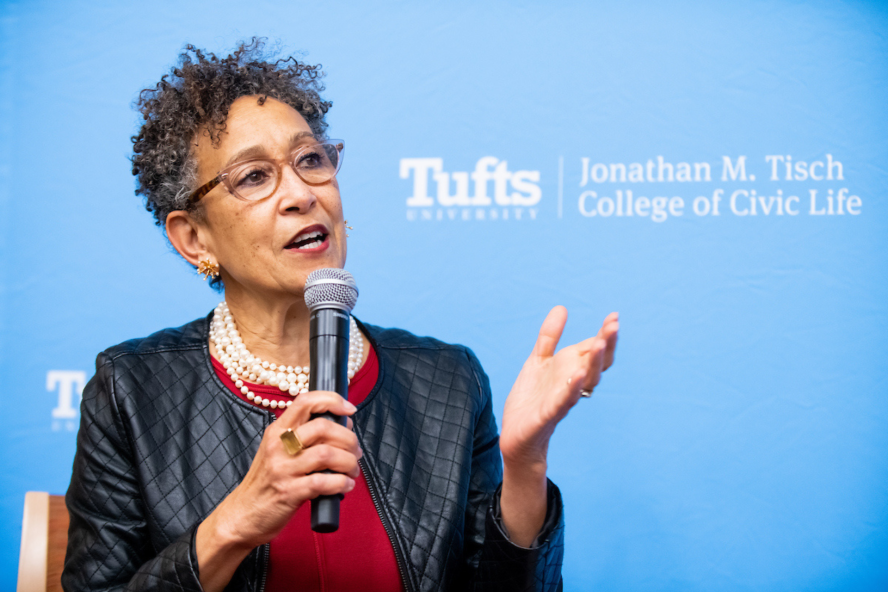 Dayna Cunningham speaks in front of background with Johnathan M. Tisch College of Civic Life Logo