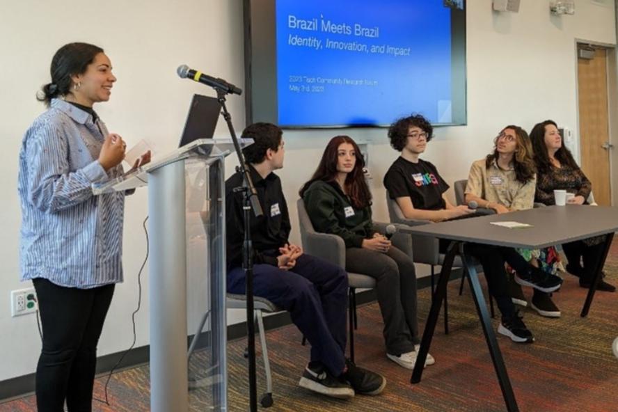 Students on a panel in a room with a lectern and table