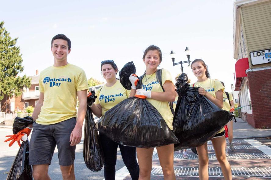Students holding garbage bags on city sidewalks