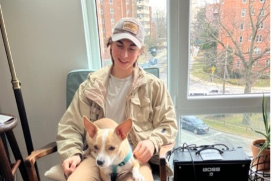 Image of Elia Goldman, civic semester student, sitting in front of a window with a dog