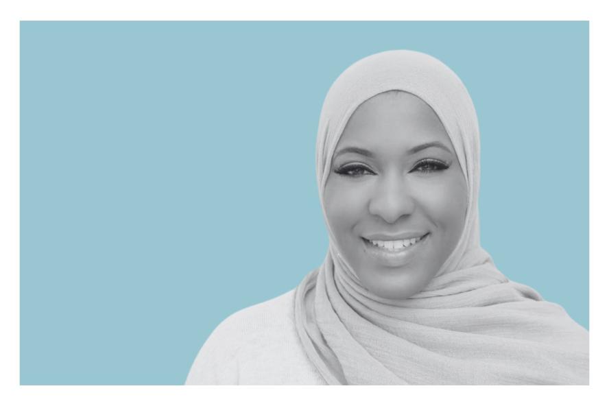Ibtihaj Muhammad smiling against a green background. 