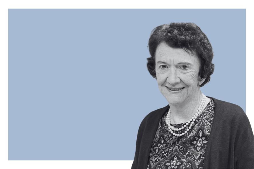 A smiling woman against a pale blue background. 