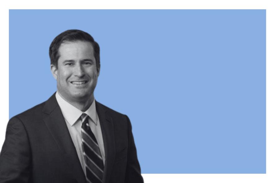 Man smiling against a blue background. 