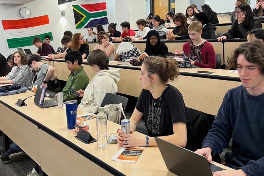 Students sit in a classroom with flags on the wall