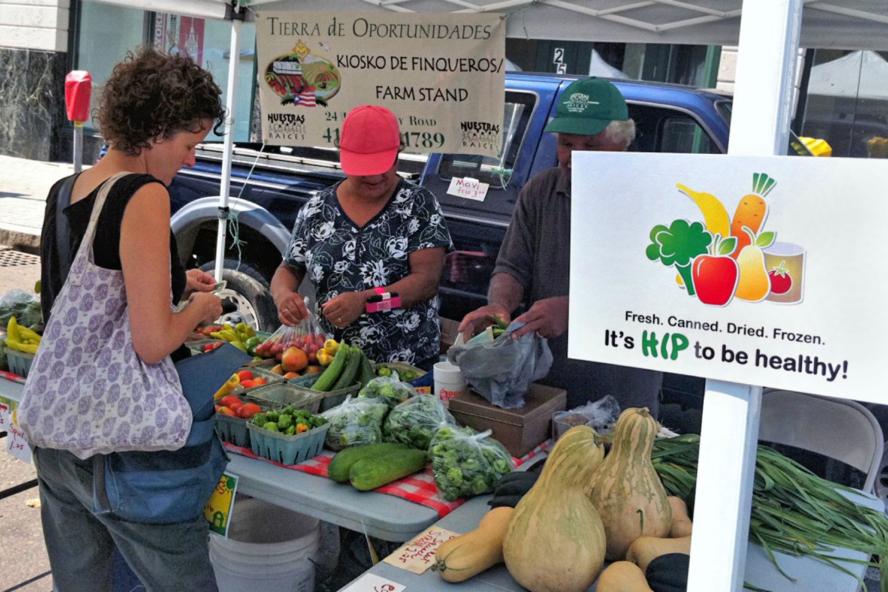 Farmers market stand selling produce with a sign promoting HIP 