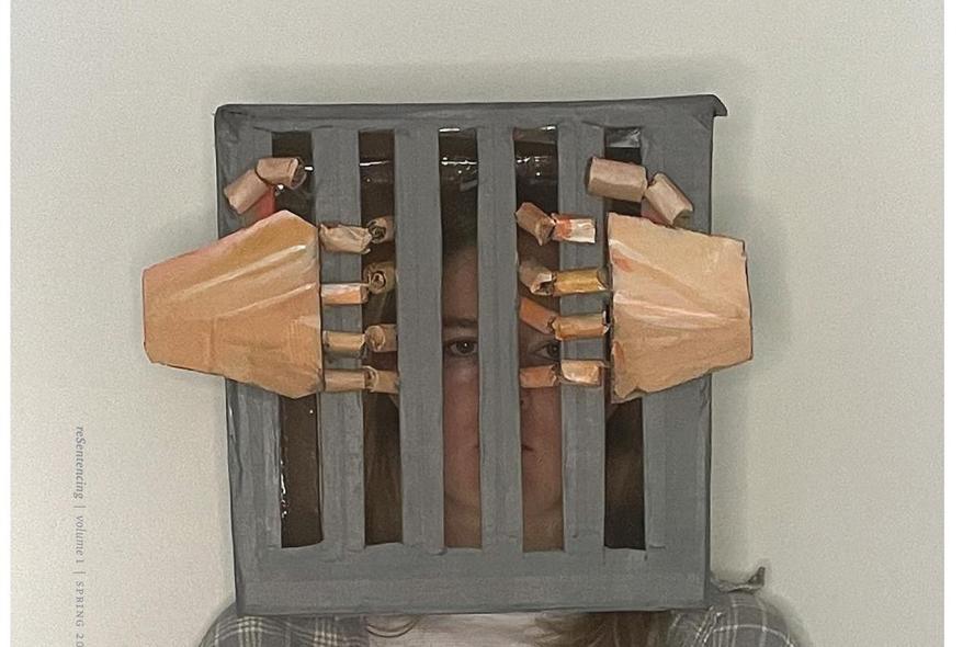 A woman wears a sculpture that shows her head behind bars.