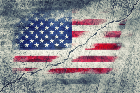 an American flag painted on a concrete wall, with a crack dividing the flag in two