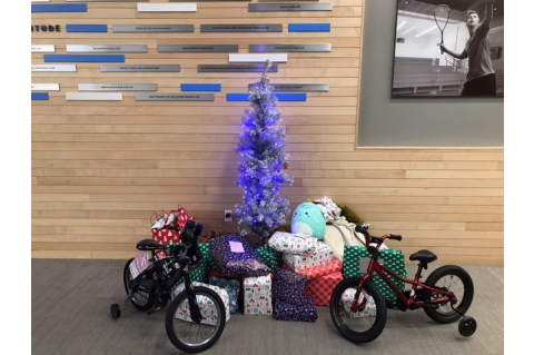 small blue tree surrounded by gifts and two bicycles