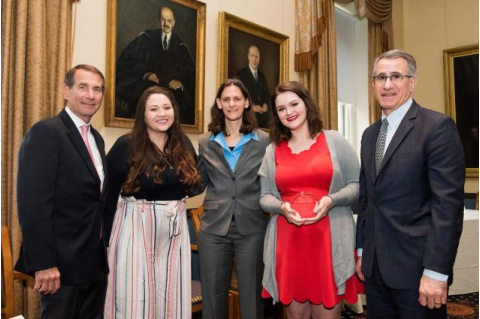 student accepting the Presidential Award for Civic Life next to several people