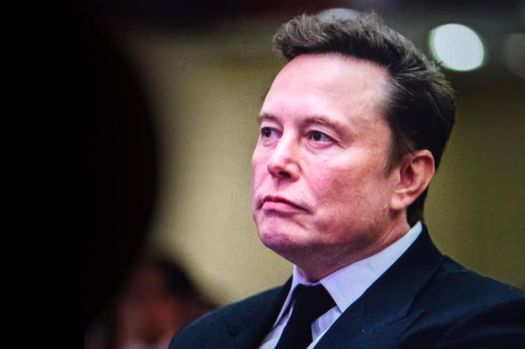 Head and shoulders photo of Elon Musk, dressed in a suit and tie