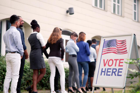 Young people stand in line at a polling place. 